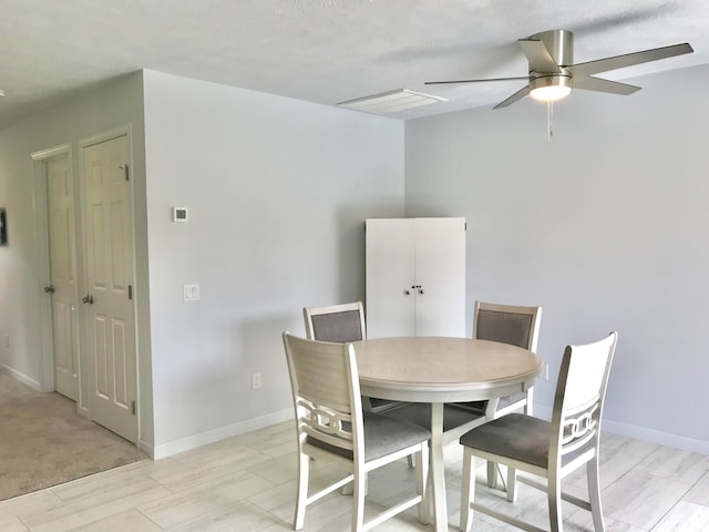 dining room with a textured ceiling, light hardwood / wood-style floors, and ceiling fan