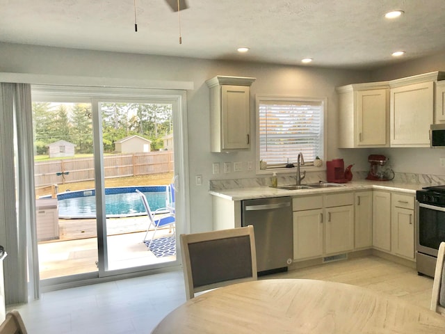 kitchen featuring cream cabinetry, appliances with stainless steel finishes, a textured ceiling, and sink