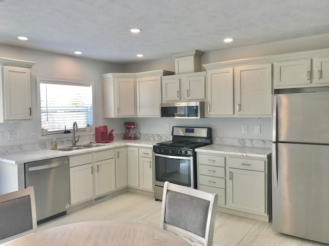 kitchen featuring a textured ceiling, stainless steel appliances, and sink