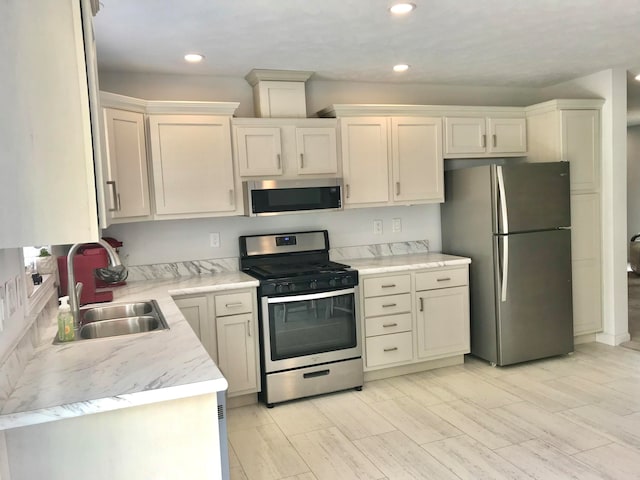 kitchen with appliances with stainless steel finishes, light wood-type flooring, and sink