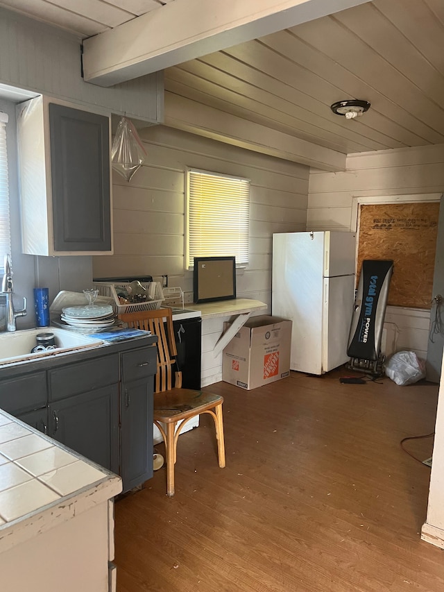 kitchen featuring gray cabinetry, wooden walls, light hardwood / wood-style flooring, and white refrigerator