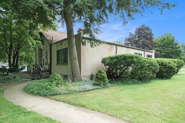 801 Portage Ave, Three Rivers, MI 49093 - view of side of home featuring brick siding, a lawn, and a wooden deck