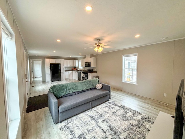 living room with light hardwood / wood-style floors, ceiling fan, and ornamental molding