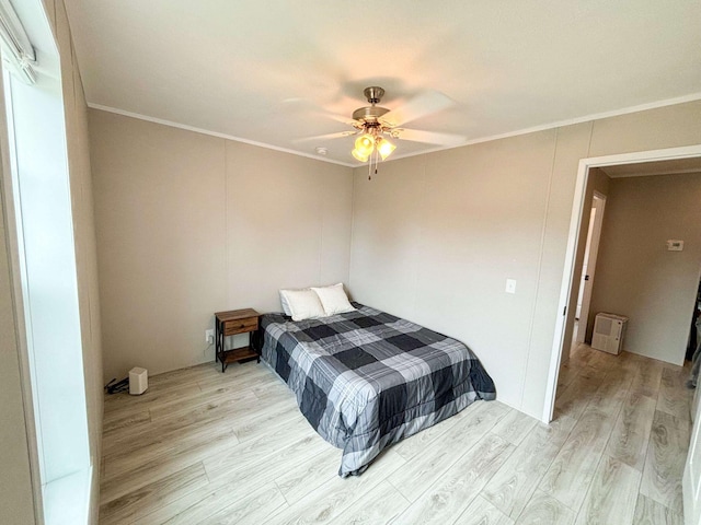 bedroom featuring ceiling fan, light wood-type flooring, and crown molding