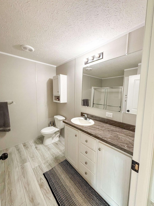 bathroom with an enclosed shower, vanity, a textured ceiling, wood-type flooring, and toilet