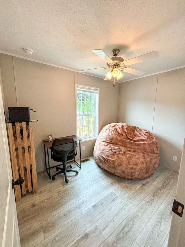 office area with ceiling fan, light hardwood / wood-style flooring, crown molding, and a textured ceiling