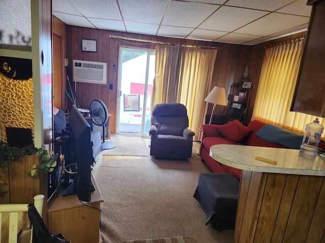 carpeted living room featuring a drop ceiling, an AC wall unit, and wooden walls