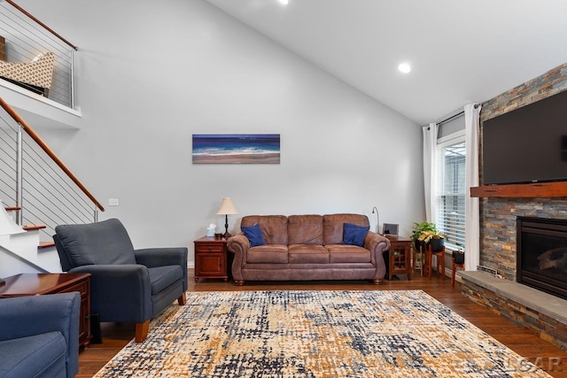 living room featuring high vaulted ceiling, dark hardwood / wood-style floors, and a stone fireplace