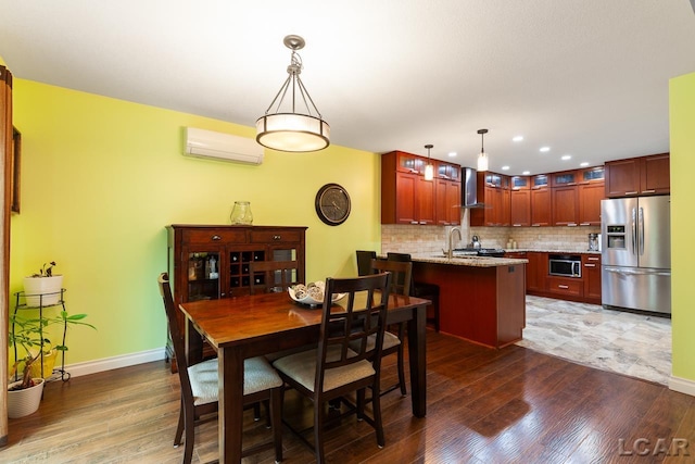 dining room featuring sink, an AC wall unit, and dark wood-type flooring