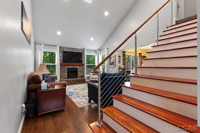 living room featuring dark hardwood / wood-style flooring, a stone fireplace, and vaulted ceiling