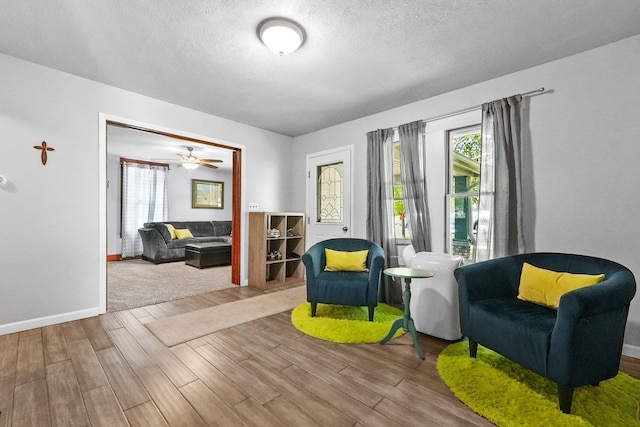 sitting room with ceiling fan, hardwood / wood-style floors, and a textured ceiling