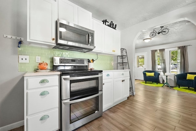 kitchen with white cabinets, appliances with stainless steel finishes, and light hardwood / wood-style floors