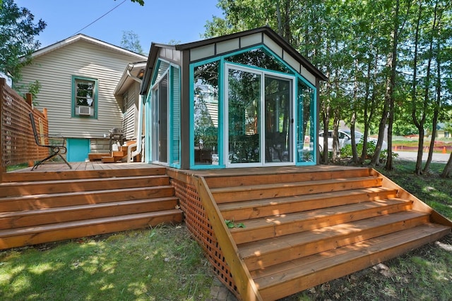 rear view of house featuring a sunroom and a deck