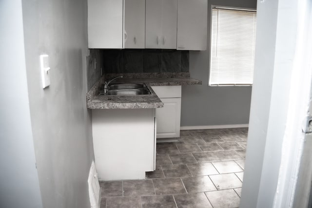 kitchen featuring white cabinets, sink, and dark tile patterned flooring