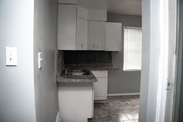 kitchen with white cabinetry, sink, and dark tile patterned floors