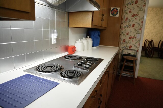 3447 200th Ave, Reed City, MI 49677 - kitchen featuring light countertops, brown cabinetry, stainless steel electric cooktop, decorative backsplash, and wall chimney range hood