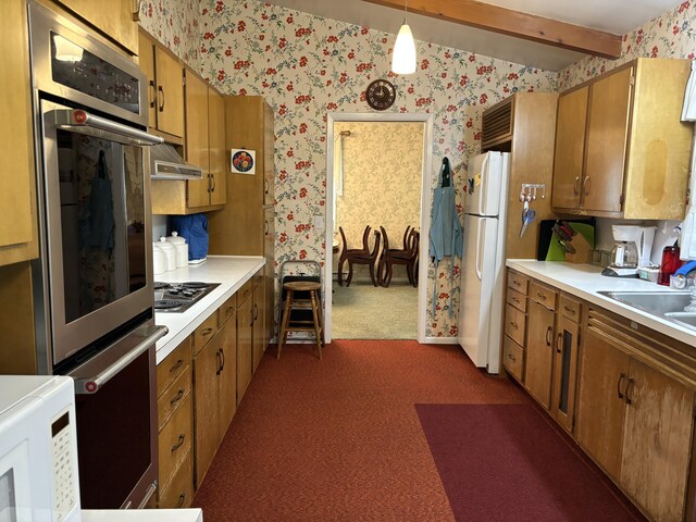 3447 200th Ave, Reed City, MI 49677 - kitchen with wallpapered walls, appliances with stainless steel finishes, dark colored carpet, brown cabinets, and light countertops