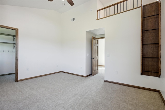 spare room featuring ceiling fan, light colored carpet, and high vaulted ceiling