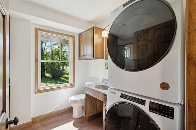 washroom featuring stacked washer / drying machine and dark hardwood / wood-style flooring