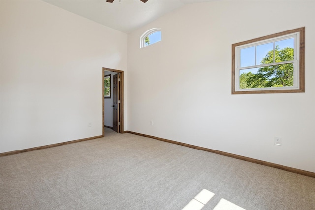 spare room with ceiling fan, light colored carpet, and vaulted ceiling