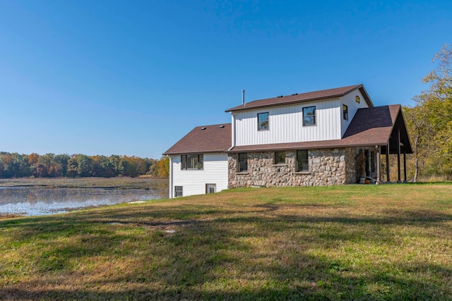 back of property with a water view and a yard