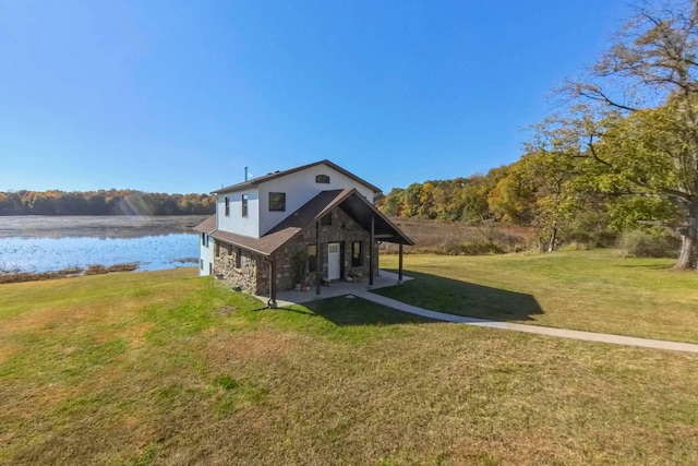 rear view of house with a yard, a water view, and a patio area