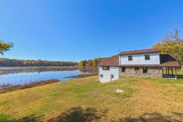 back of house with a water view and a yard