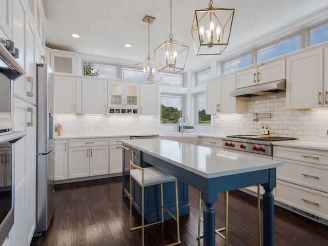 kitchen featuring pendant lighting, dark wood-type flooring, white cabinets, a kitchen breakfast bar, and decorative backsplash