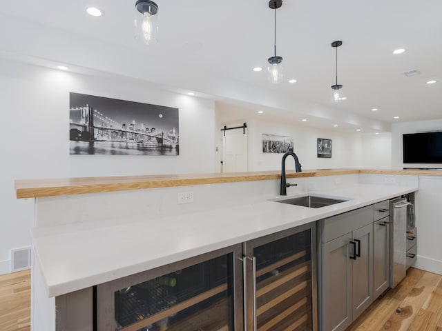 kitchen with gray cabinets, light hardwood / wood-style floors, sink, and wine cooler