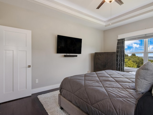 bedroom featuring a tray ceiling, ceiling fan, and dark wood-type flooring