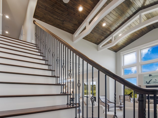 stairs featuring beam ceiling, high vaulted ceiling, a wealth of natural light, and wooden ceiling