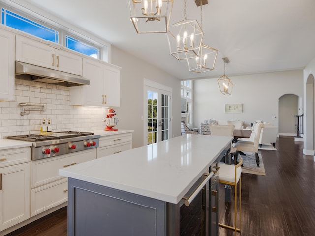 kitchen featuring hanging light fixtures, white cabinets, a center island, dark hardwood / wood-style floors, and stainless steel gas stovetop