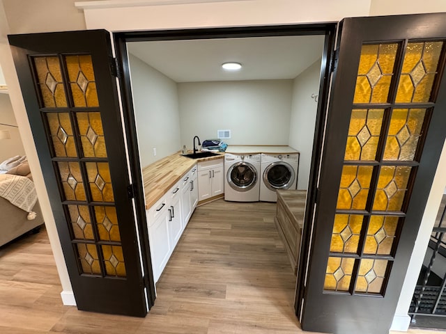 laundry room with washing machine and dryer, cabinets, light hardwood / wood-style floors, and sink