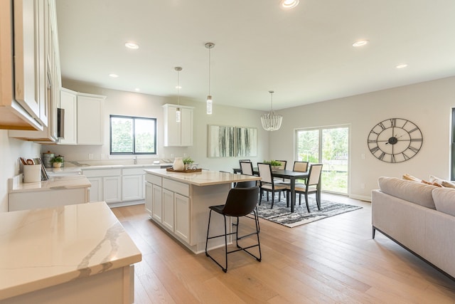 kitchen featuring white cabinets, a healthy amount of sunlight, a kitchen island, and pendant lighting