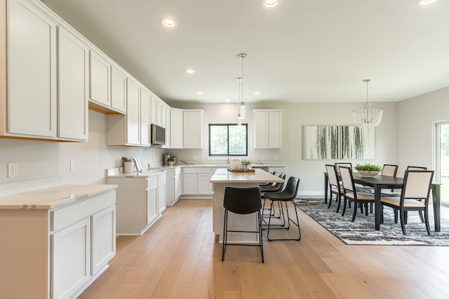 kitchen with white cabinetry, plenty of natural light, a kitchen island, and decorative light fixtures