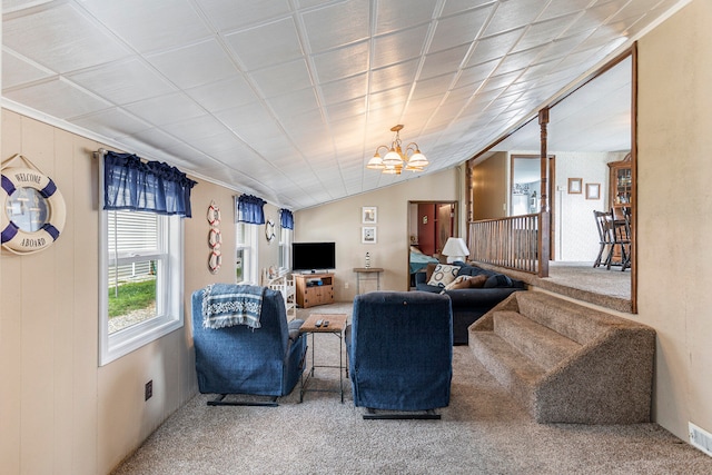 carpeted living room with wooden walls, a chandelier, and vaulted ceiling