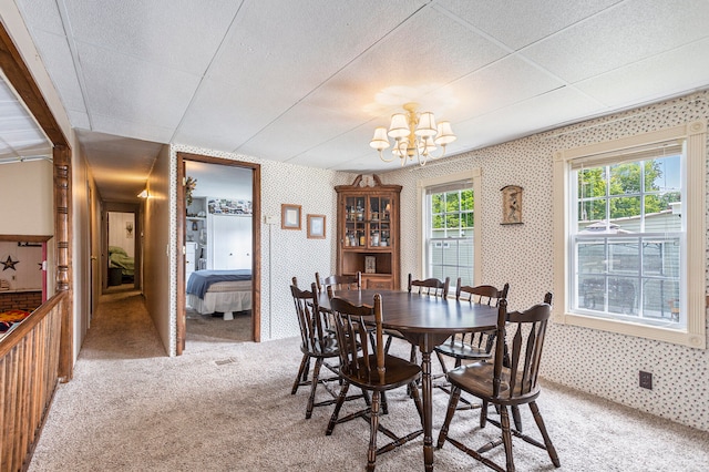 dining space with carpet floors and a notable chandelier