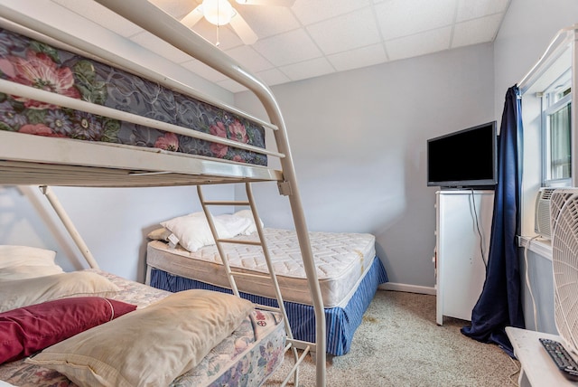 bedroom featuring carpet, a drop ceiling, and ceiling fan