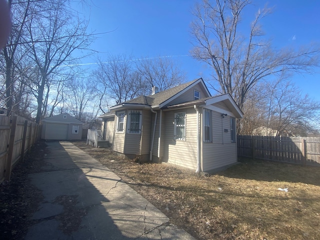 view of side of home featuring an outbuilding, fence, a garage, and driveway