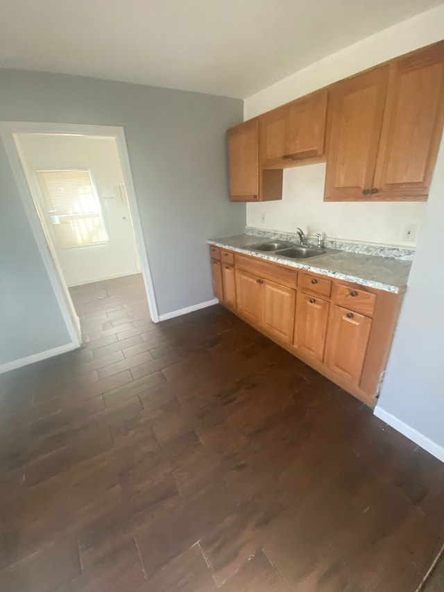 kitchen with light countertops, dark wood-type flooring, baseboards, and a sink