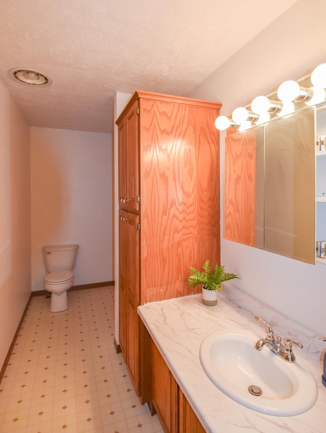 bathroom with vanity, toilet, and a textured ceiling