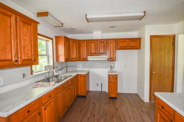 kitchen featuring light stone counters, sink, range hood, and dark wood-type flooring