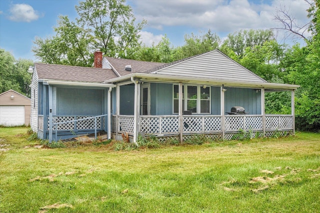 single story home with an outbuilding, a garage, covered porch, and a front lawn