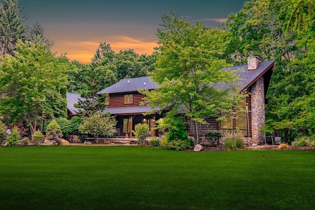 back house at dusk with a lawn