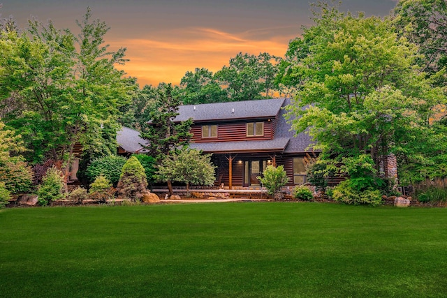 back house at dusk featuring a lawn