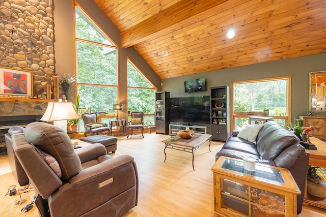 living room with light hardwood / wood-style floors, a stone fireplace, wood ceiling, and a wealth of natural light