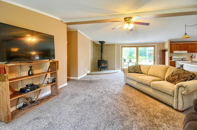 carpeted living room with a textured ceiling, a wood stove, ceiling fan, and crown molding