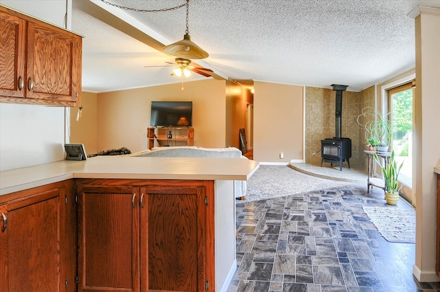 kitchen featuring lofted ceiling, a wood stove, ceiling fan, a textured ceiling, and kitchen peninsula