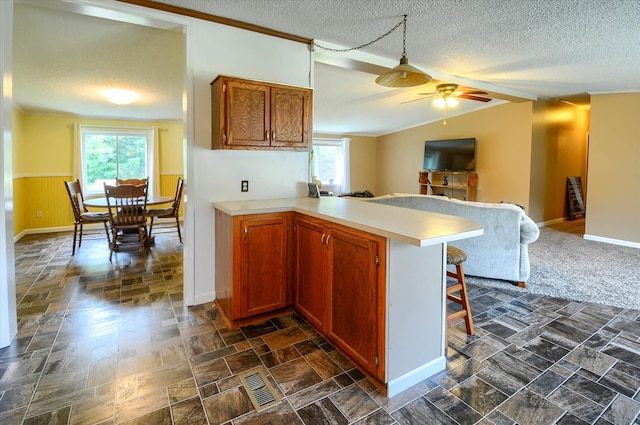 kitchen with a textured ceiling, ceiling fan, kitchen peninsula, and a breakfast bar area