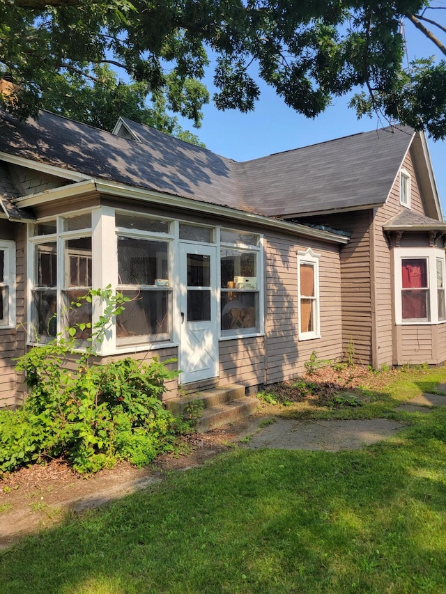 437 Ada Ave, Muskegon, MI 49442 - view of front facade featuring a front yard, entry steps, a sunroom, and roof with shingles